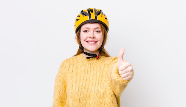 Mooie vrouw met rood hoofd voelt zich trots glimlachend positief met duimen omhoog fietsconcept