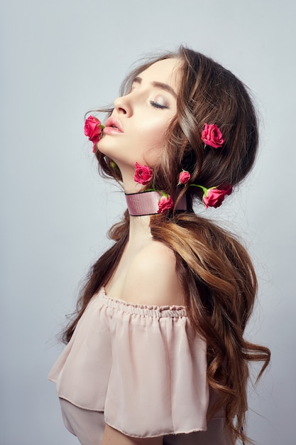 Mooie vrouw met roze bloemen in haar lange haar