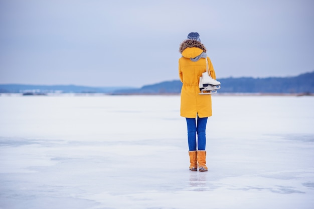 Mooie vrouw met schaatsen in het midden van een bevroren meer