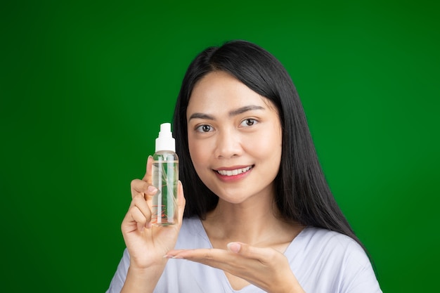 Mooie vrouw met serum spray fles op groen scherm