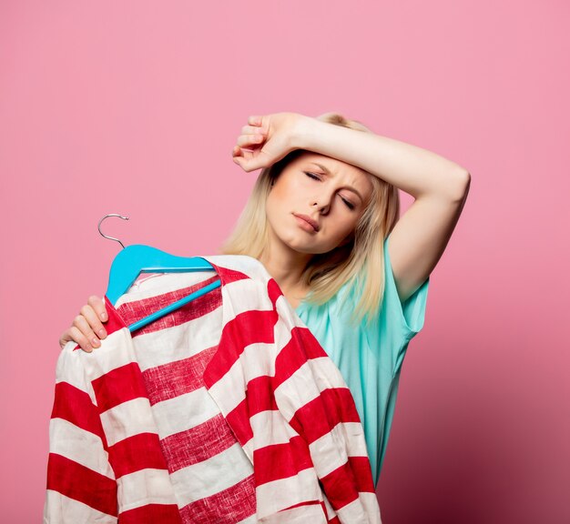 Mooie vrouw met shirt op een hanger op roze muur