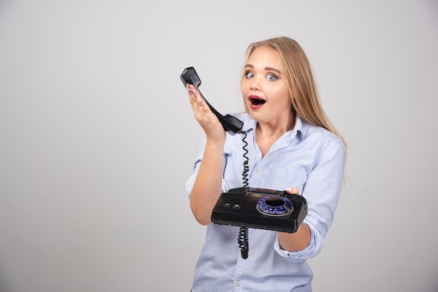 mooie vrouw met telefoon en pratende geïsoleerde grijze muur.