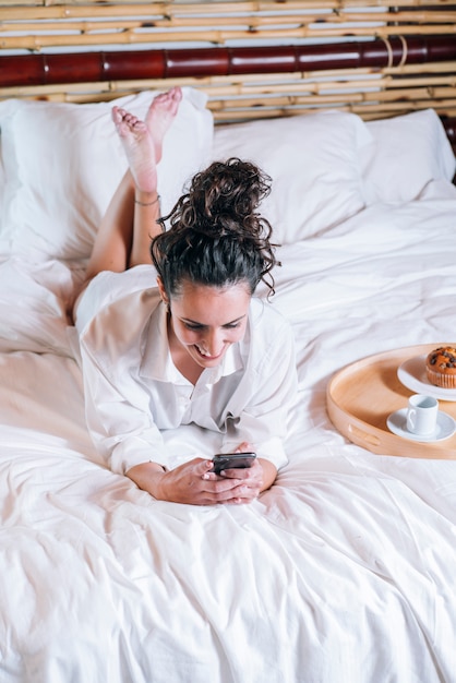 Mooie vrouw met telefoon in bed