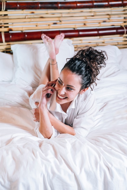 Mooie vrouw met telefoon in bed