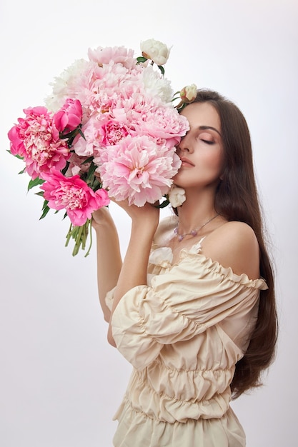 Mooie vrouw met veel roze bloemen in haar handen.