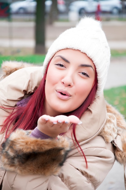 Mooie vrouw met winterkleren bij het sturen van een luchtkus aan de camera