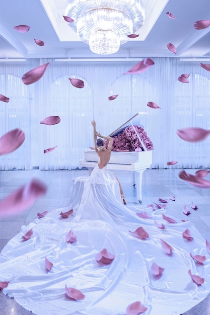 Mooie vrouw met witte piano en pioenrozen bloemen in witte studio