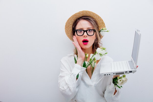 Mooie vrouw met witte rozen in kokers die met laptop iets zoeken. Lente concept of Valentijnsdag vakantie