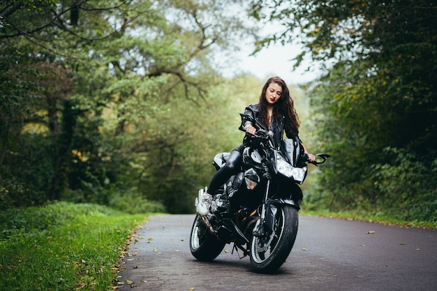Mooie vrouw, met zwart krullend haar, in een zwart leren jasje, zittend op een sportieve motorfiets