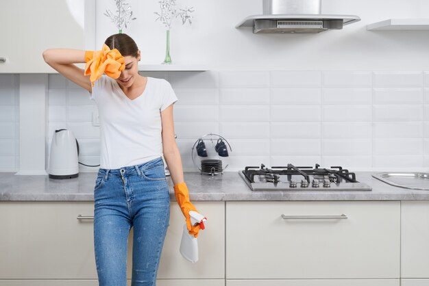 Mooie vrouw moe na het schoonmaken van de keuken