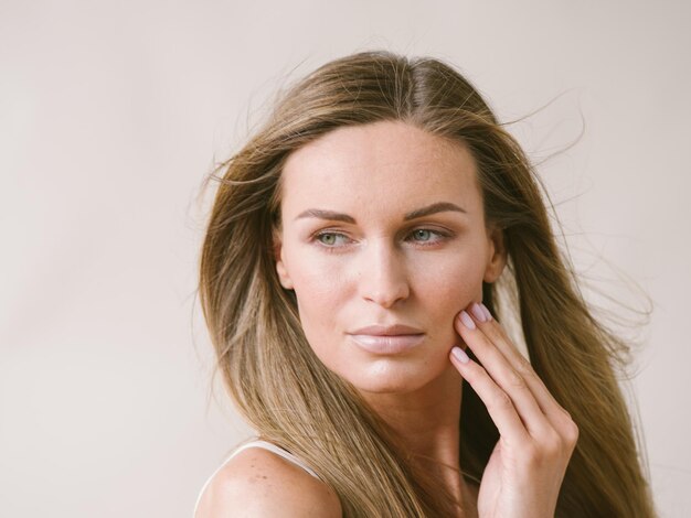 Mooie vrouw natuurlijke portret meisje met lang blond haar over wit grijze muur. Studio opname.