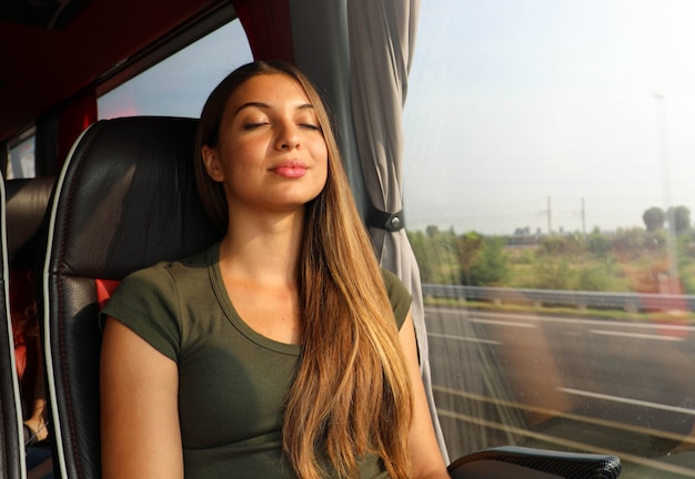 Mooie vrouw ontspannen en slapen zittend in comfortabele bus. bus- of treinreizigers die zittend op een stoel reizen en slapen.