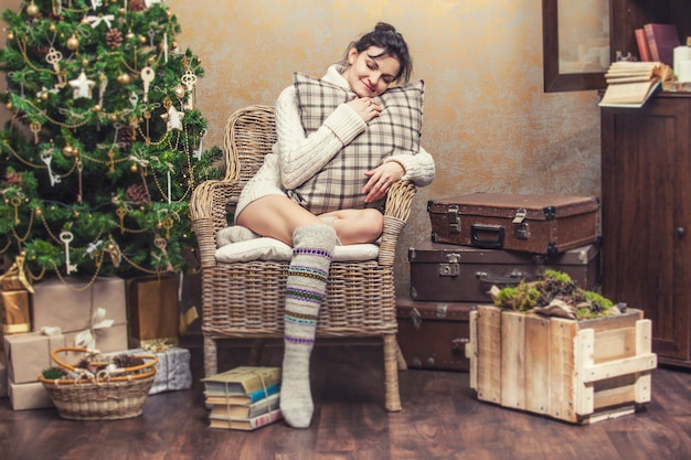 Mooie vrouw ontspannen zittend in een stoel met kussens in het kerstinterieur