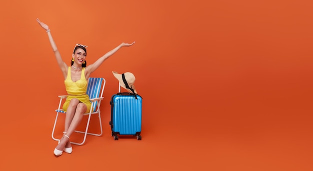 Mooie vrouw ontspannen zittend op een strandstoel met koffer in studio zomer oranje achtergrond