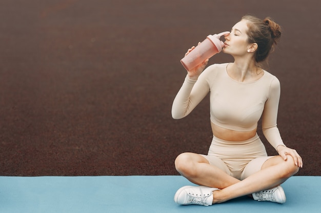 Mooie vrouw ontspannende yoga in het stadion. Trainen en strekken op de gymmat.