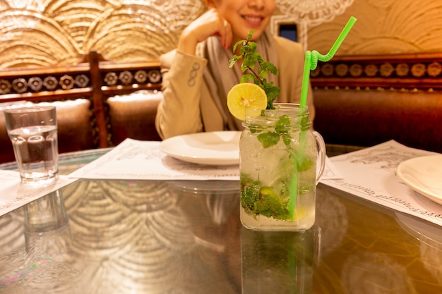 Mooie vrouw op achtergrond die verse mojitococktail in een restaurant hebben.