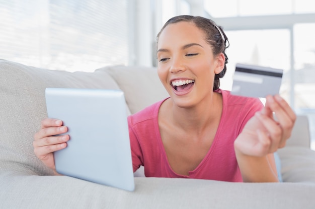 Mooie vrouw op bank met een tablet en een creditcard