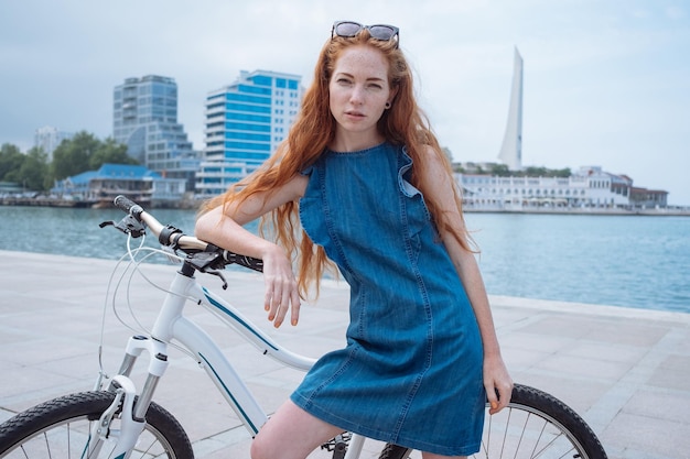 Mooie vrouw op de fiets Lifestyle en gezondheid in de stad Vrolijke roodharige jonge vrouw krijgt plezier van wandelen door de stad