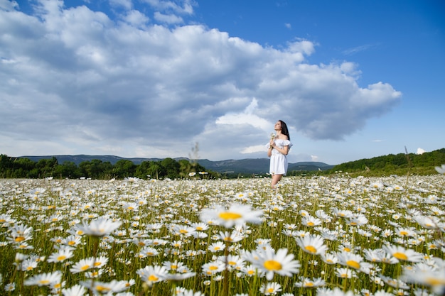 Mooie vrouw op een bloem granden die in openlucht van haar tijd geniet