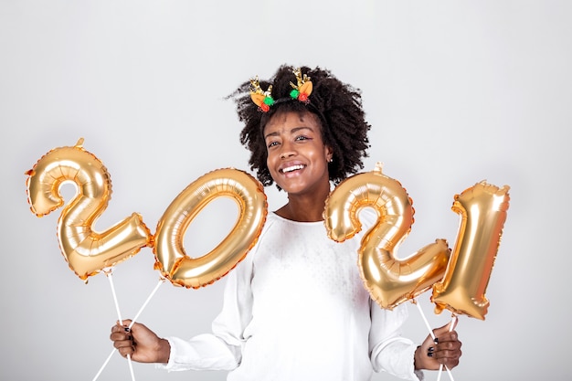 Mooie vrouw op een nieuwjaarsfeest: spelen met gouden ballonnen nummers 2021