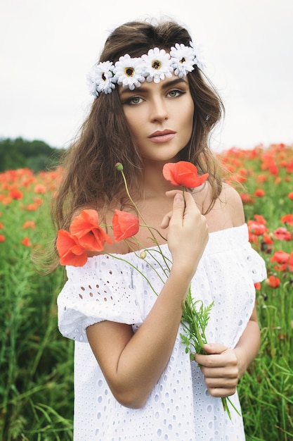 Mooie vrouw op gebied met heel wat papaverbloemen