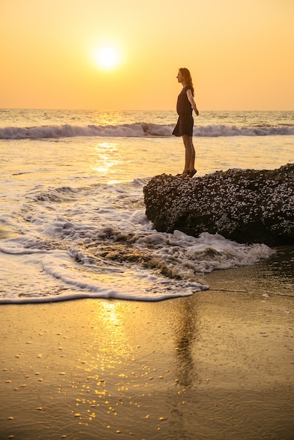 Mooie vrouw op het strand bij zonsondergang