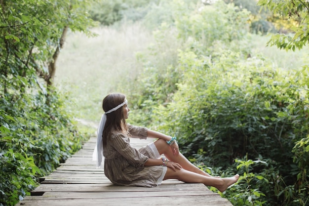 Mooie vrouw op oude houten brug in het bos