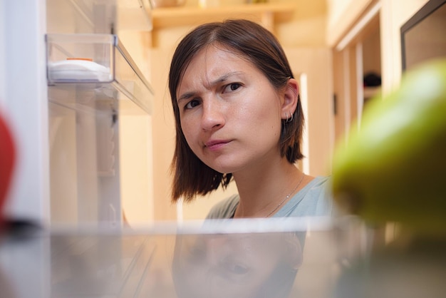 Mooie vrouw op zoek naar voedsel in de koelkast