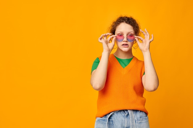 Mooie vrouw oranje sweatshirts zonnebril veelkleurige glazen leveren gele achtergrond ongewijzigd