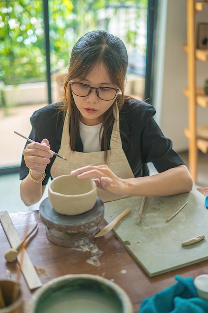 Mooie vrouw pottenbakker bezig met pottenbakkers wiel maken van keramische pot van klei in aardewerk workshop focus hand jonge vrouw klei product onderdeel vastmaken aan toekomstig keramisch product aardewerk workshop