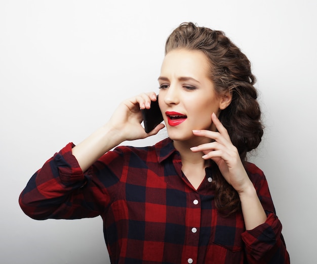 Mooie vrouw praten over de telefoon over wit oppervlak