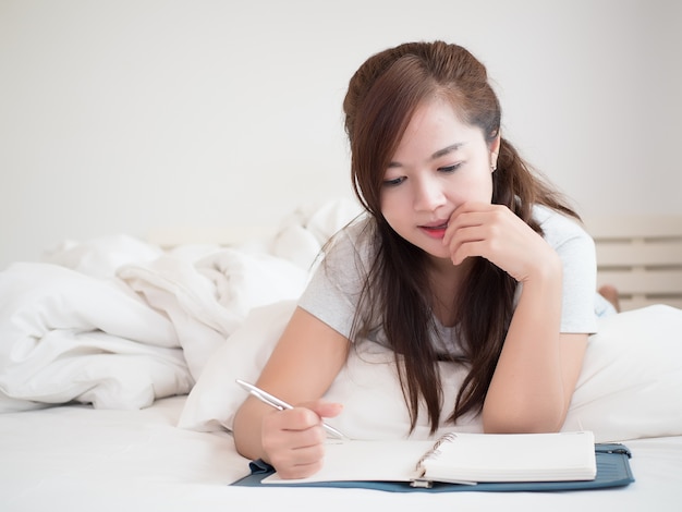 mooie vrouw schrijft dagboek op haar bed