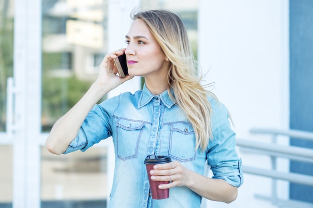 Mooie vrouw spreekt aan de telefoon en drinkt koffie