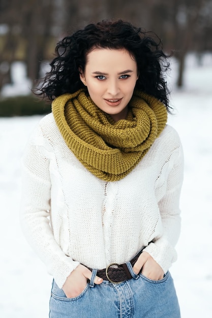 Mooie vrouw staat buiten sneeuwpark bos weer winter gekleed gebreide warme trui en sjaal
