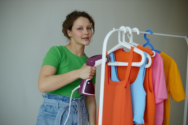 Mooie vrouw strijken kleren op een hanger garderobe geïsoleerde achtergronden ongewijzigd