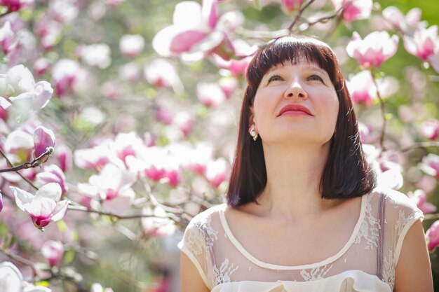 mooie vrouw tegen de achtergrond van magnolia bloemen.