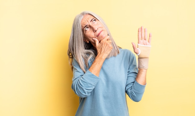 Mooie vrouw van middelbare leeftijd denken, twijfelachtig en verward voelen. handverband concept