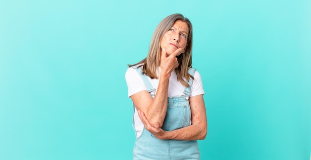 Mooie vrouw van middelbare leeftijd die denkt, zich twijfelachtig en verward voelt