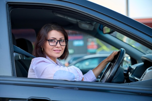 Mooie vrouw van middelbare leeftijd die een auto bestuurt