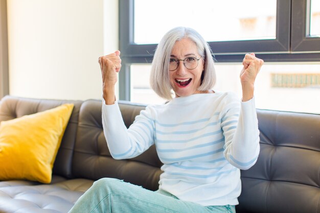 Mooie vrouw van middelbare leeftijd die een ongelooflijk succes viert als een winnaar, die er opgewonden en blij uitziet en zegt: neem dat!