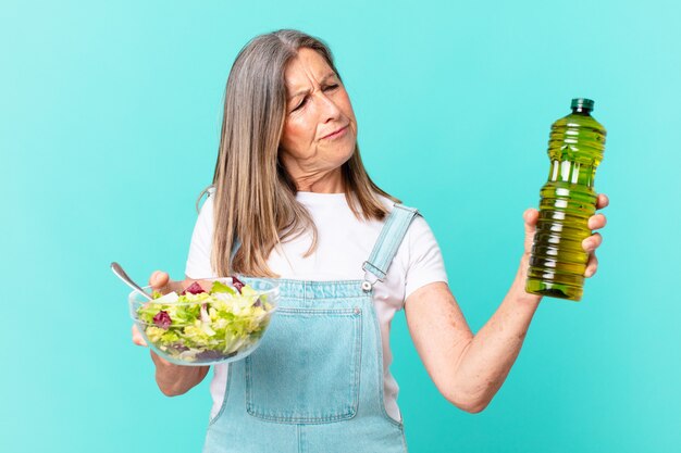 Mooie vrouw van middelbare leeftijd die een salade heeft.