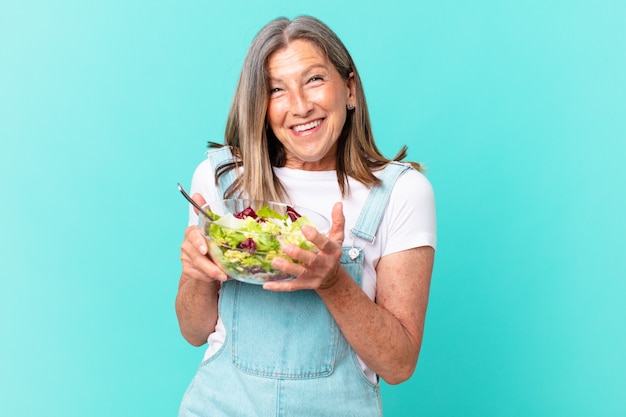 Mooie vrouw van middelbare leeftijd die een salade heeft.