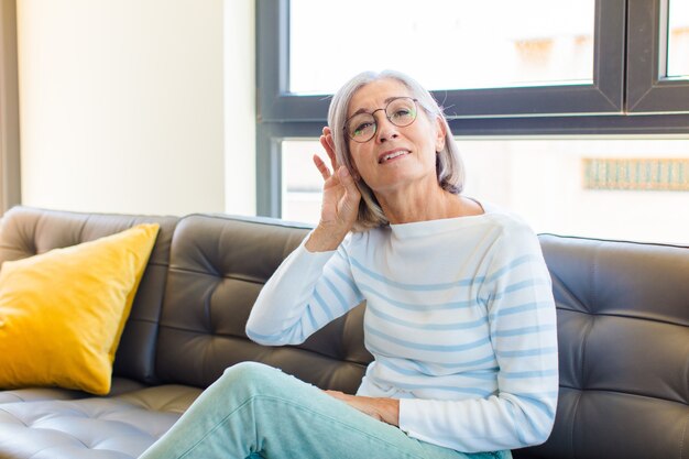 Mooie vrouw van middelbare leeftijd die lacht, nieuwsgierig naar de zijkant kijkt