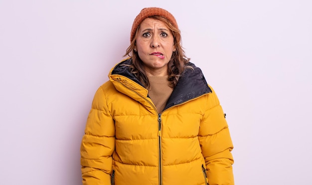 Mooie vrouw van middelbare leeftijd die verbaasd en verward kijkt. winter concept