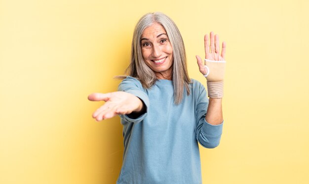 Mooie vrouw van middelbare leeftijd die vrolijk lacht met vriendelijk en een concept aanbiedt en toont. handverband concept