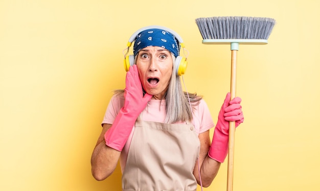 Mooie vrouw van middelbare leeftijd die zich geschokt en bang voelt. huishoud- en bezemconcept