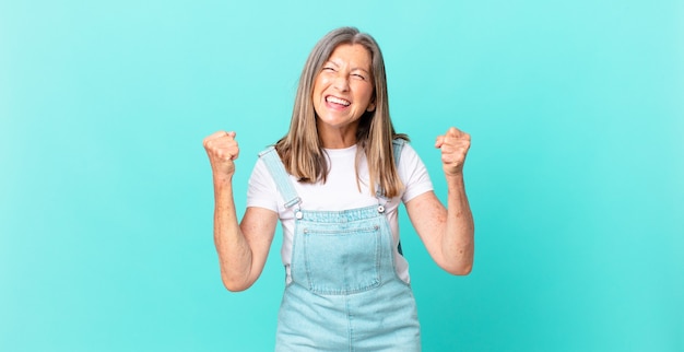 mooie vrouw van middelbare leeftijd die zich geschokt voelt, lacht en succes viert