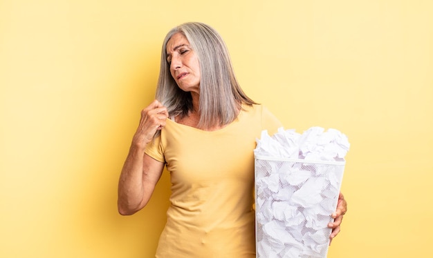 Mooie vrouw van middelbare leeftijd die zich gestrest voelt, angstig, moe en gefrustreerd, mislukt concept van papieren ballen