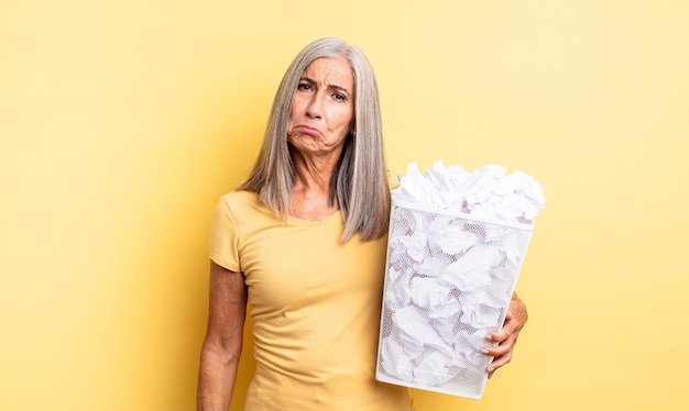 Mooie vrouw van middelbare leeftijd die zich verdrietig en zeurt met een ongelukkige blik en huilt. papieren ballen mislukking concept