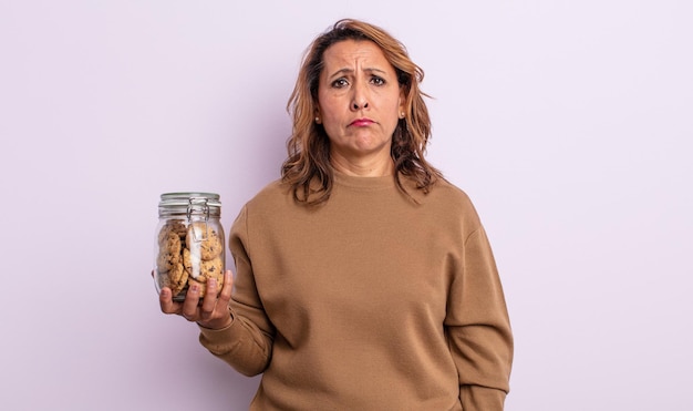 Foto mooie vrouw van middelbare leeftijd die zich verdrietig en zeurt met een ongelukkige blik en huilt. zelfgemaakte koekjes concept